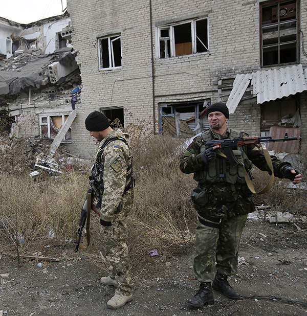 Ukrainian servicemen walk in the yard of a destroyed building in the Pisky village near Donetsk on October 26, 2015.