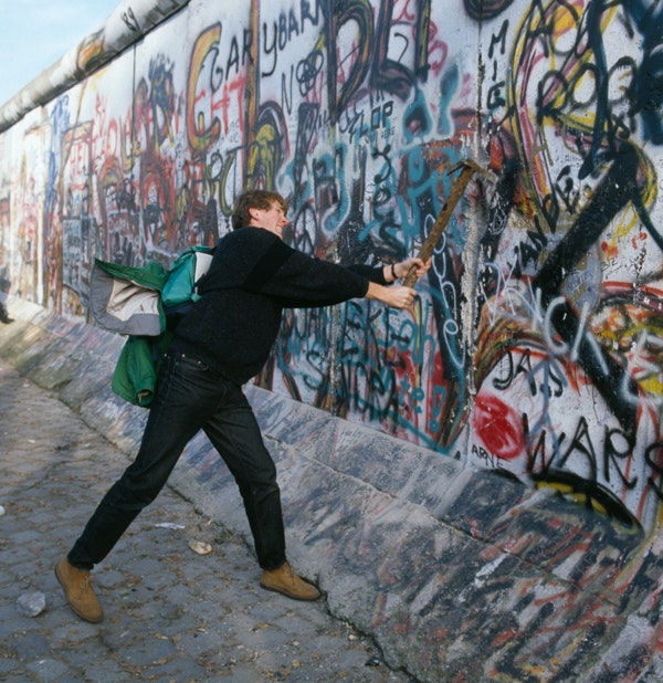 A man wields a pickaxe to participate in the destruction of the Berlin Wall, November 10, 1989. (Jacques Langevin/Sygma/Sygma via Getty Images)