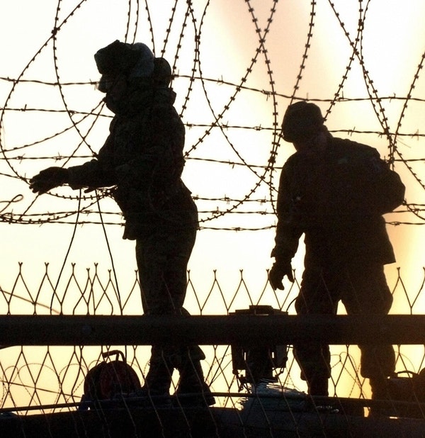 South Korean soldiers check barbed wire fence along the border in Paju, near the Demilitarized Zone the two Koreas, February 10, 2005.  (Jung Je/AFP/Getty Images)